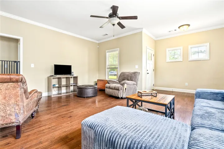 Hardwood floors and generous ceiling height define this welcoming, well-lit living space.