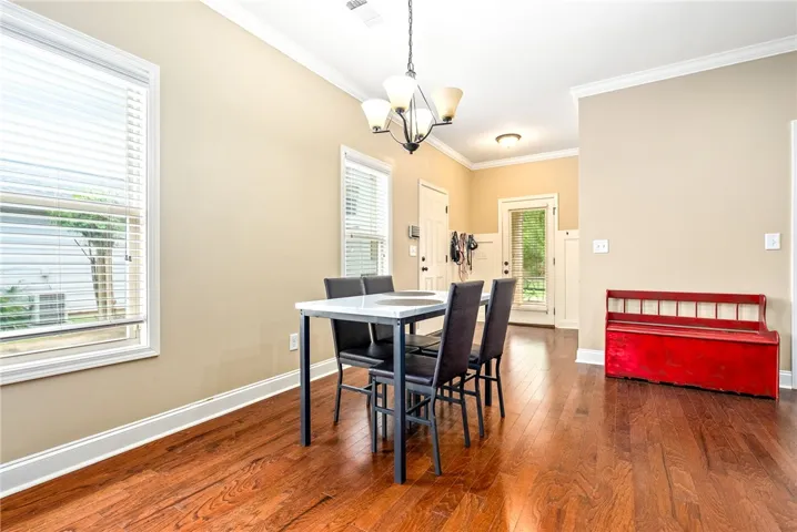 Hardwood floors flow through this dining area, illuminated by natural light and a chic overhead fixture.