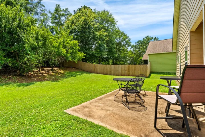 A spacious backyard with mature trees and a private patio offers tranquil outdoor living.