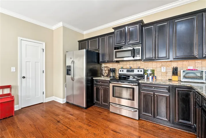 Rich hardwood flooring complements a modern kitchen with granite counters and stainless steel appliances.