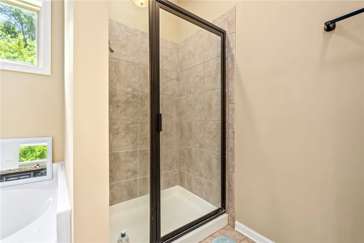 A well-lit shower enclosure with tiled walls and a clear glass door offers a refreshing retreat.
