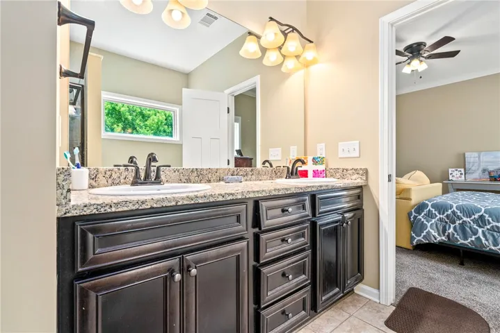 Double vanity with granite counters, ideal for a morning routine, flows into a plush bedroom.