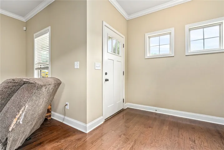 Rich hardwood floors welcome guests into this well-lit entryway, complete with a classic white door and crown molding.