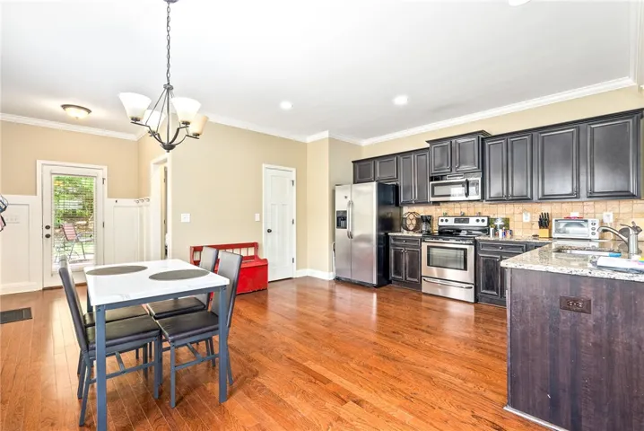 Warm hardwood flooring unites the cooking and dining spaces, with sleek stainless appliances gleaming under task lighting.