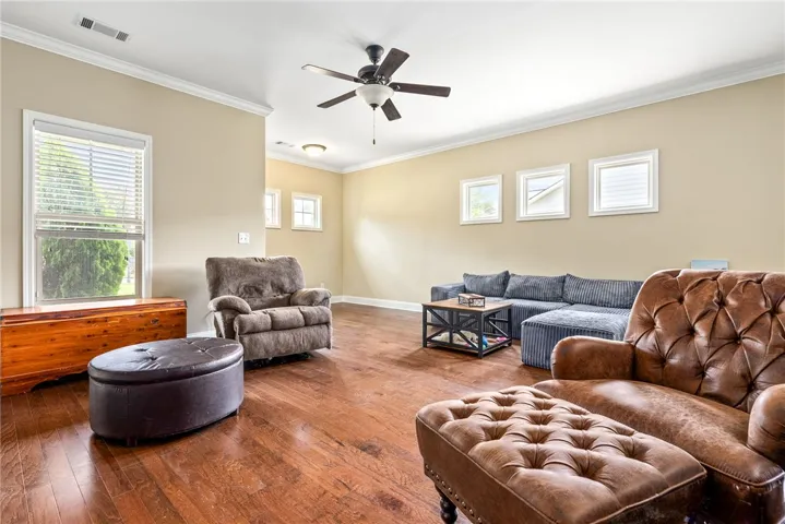 Rich hardwood floors complement this living area with crown molding and ceiling fan for comfortable relaxation.