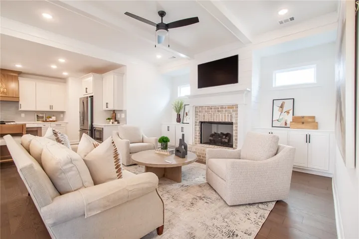 A welcoming great room, illuminated by recessed lighting, features hardwood flooring and a charming brick fireplace. Photos are not of subject property. Photos are of the same floorplan of a completed home.