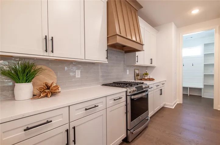 A well-appointed kitchen features a gas range and sleek countertops, with a glimpse of a convenient mudroom. Photos are not of subject property. Photos are of the same floorplan of a completed home.