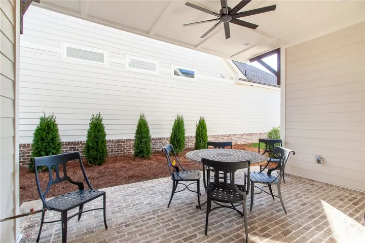 An inviting covered patio featuring a classic brick flooring and a cozy seating area. Photos are not of subject property. Photos are of the same floorplan of a completed home.