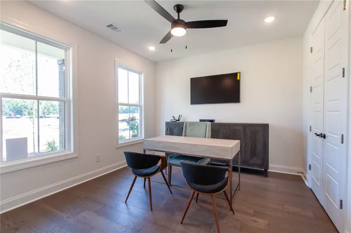 A quiet office space features rich hardwood flooring and generous natural light. Photos are not of subject property. Photos are of the same floorplan of a completed home.