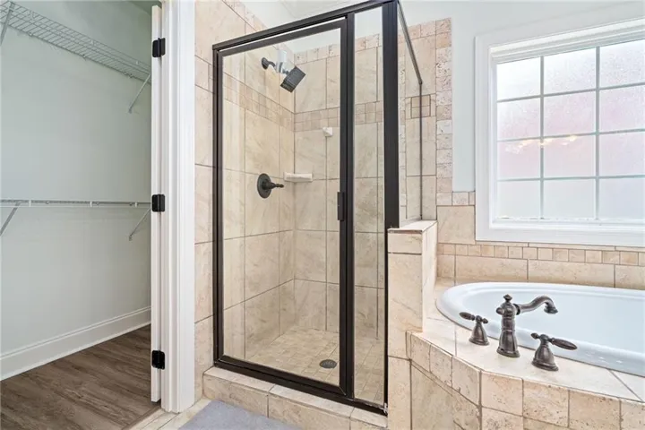 Indulge in a primary bathroom featuring a tiled walk-in shower and a spacious soaking tub.