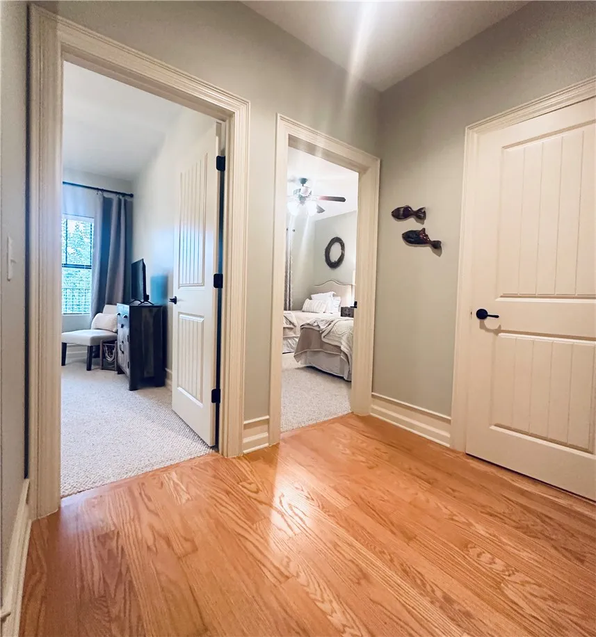 Warm hardwood flooring flows through this bright hallway connecting to inviting bedrooms.