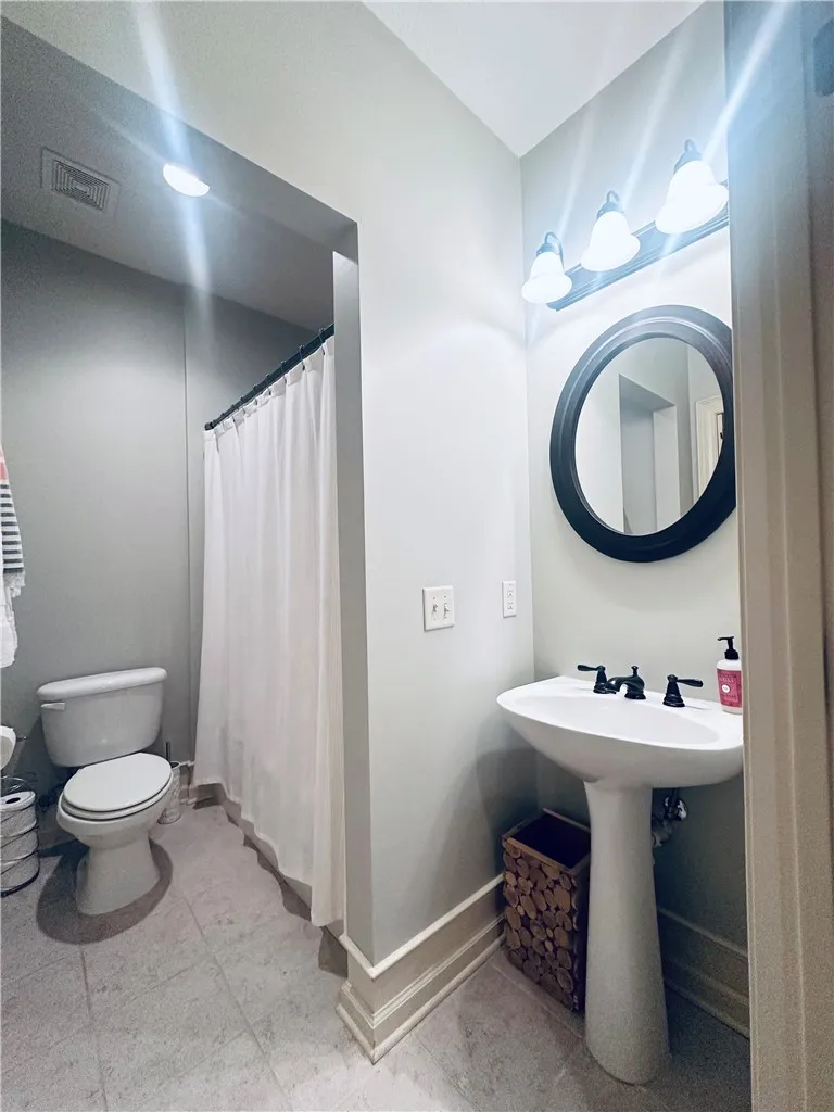 A well-appointed bath offers a pedestal sink and tile flooring.