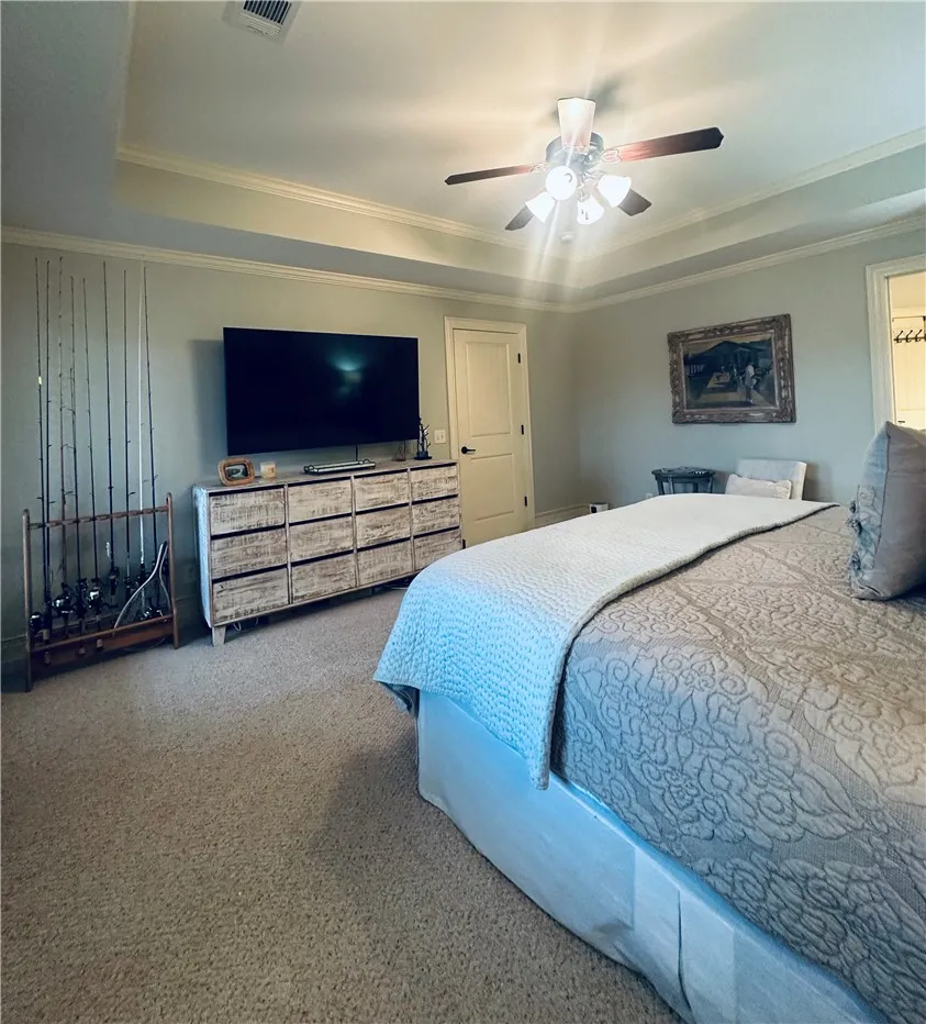 Relax in comfort within this primary bedroom, showcasing a tray ceiling and soft carpet underfoot.