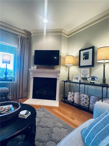 Elegant crown molding accents this living space, featuring a cozy fireplace and warm hardwood flooring.