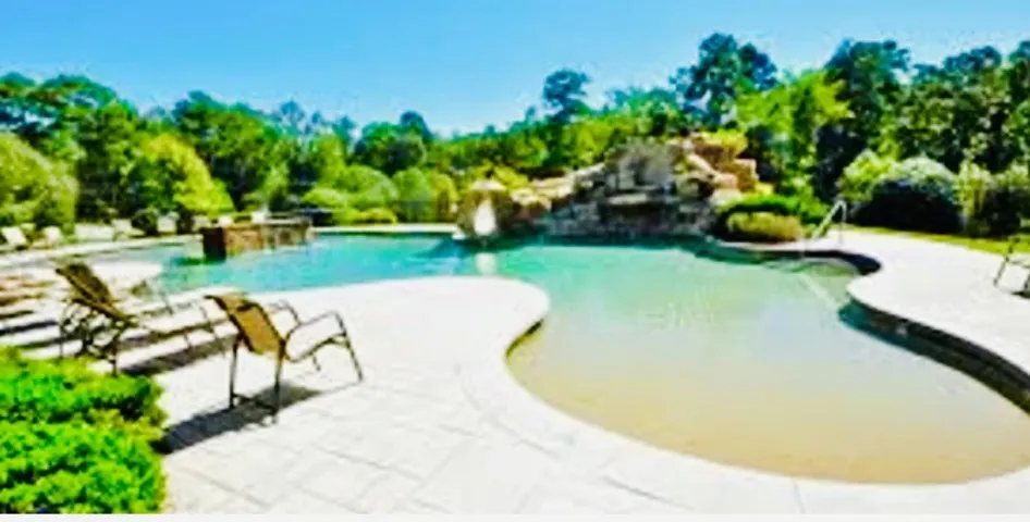 Discover a tranquil pool oasis with a rock waterfall and surrounding foliage.