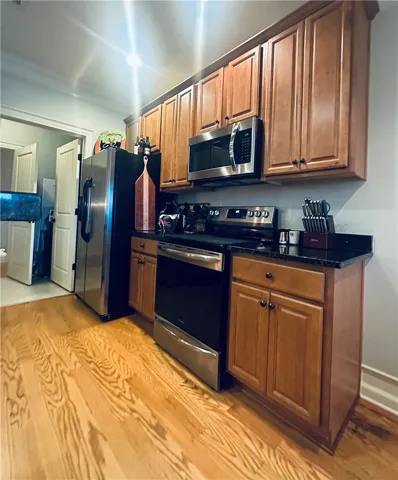 A well-equipped kitchen features sleek stainless steel appliances set against rich wood cabinetry and gleaming hardwood floors.