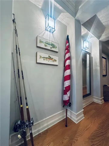 Hardwood flooring and decorative wall sconces illuminate a hallway.
