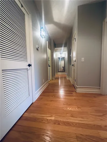 Rich hardwood flooring guides the way down this well-lit interior hallway.