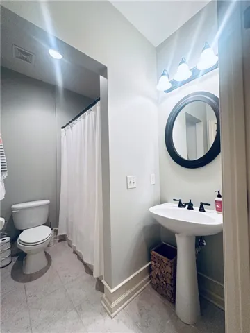 A well-appointed bath offers a pedestal sink and tile flooring.