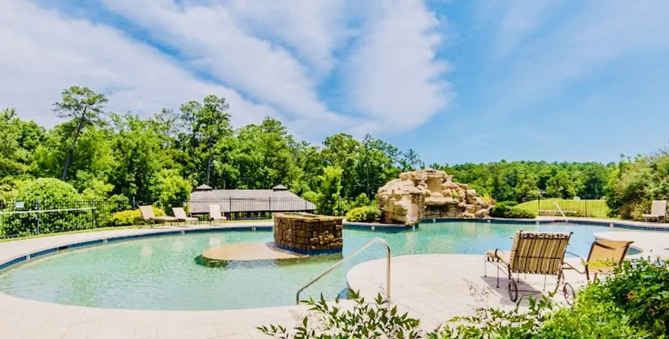 A refreshing resort-style swimming pool awaits with a rock waterfall and sun loungers.