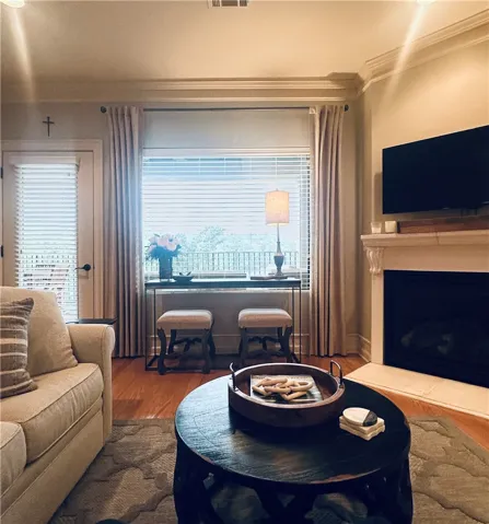 Hardwood floors and crown molding elevate this living space with a cozy fireplace.
