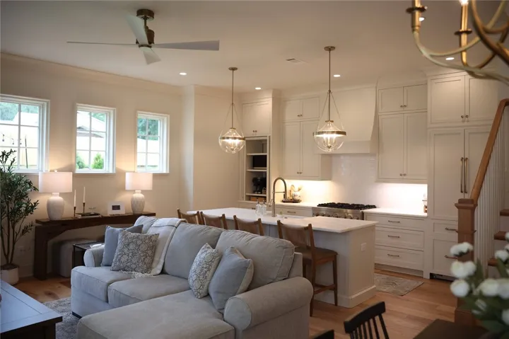 An open living space transitions into a tailored kitchen with stone counters and hardwood flooring.