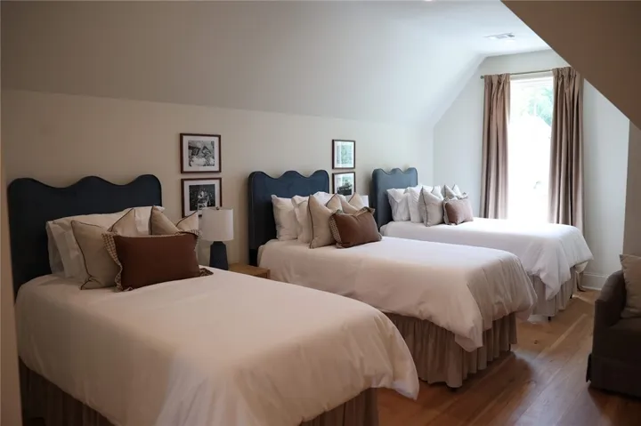 Angled ceilings and warm hardwood flooring frame a serene second-floor sleeping space.