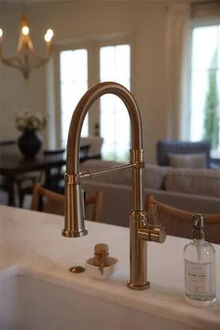 Elegant stone countertops host a modern faucet alongside views of an airy open floorplan.