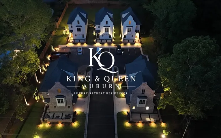 Illuminated luxury residences at night, nestled among verdant trees with a dedicated parking area.