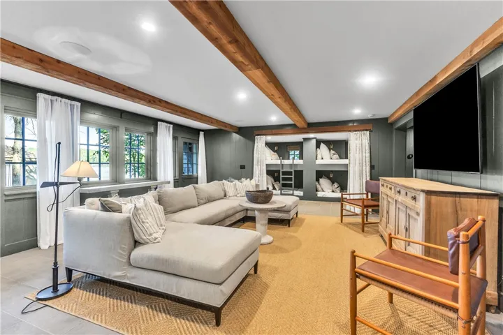 Exposed beams and recessed lighting illuminate this versatile living space with custom-built bunk beds.