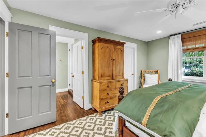 Comfortable bedroom with warm wood flooring and a view of surrounding greenery.