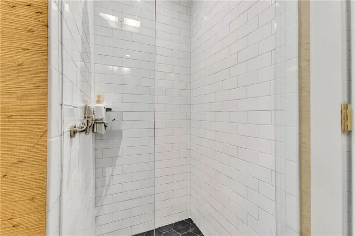 A well-lit shower features classic white subway tile and hexagonal floor tiles for timeless appeal.