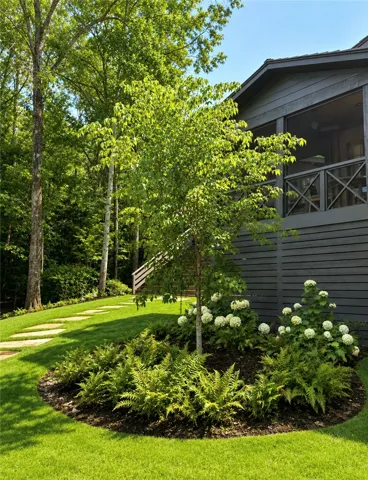Mature trees and lush landscaping frame this secluded outdoor retreat with a flagstone path.