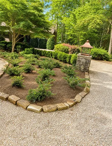 A gracefully curved stone border delineates a verdant garden bed, complementing the gravel pathway leading to the inviting home.