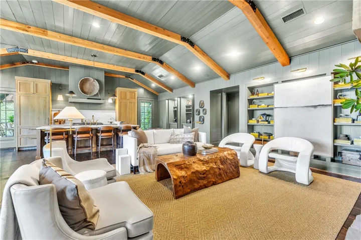 Exposed wood beams accentuate the vaulted ceilings of this naturally illuminated, inviting living area.