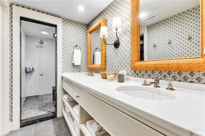 Marble countertops and dual sinks elevate this primary bathroom, featuring a glass-enclosed shower with subway tile.