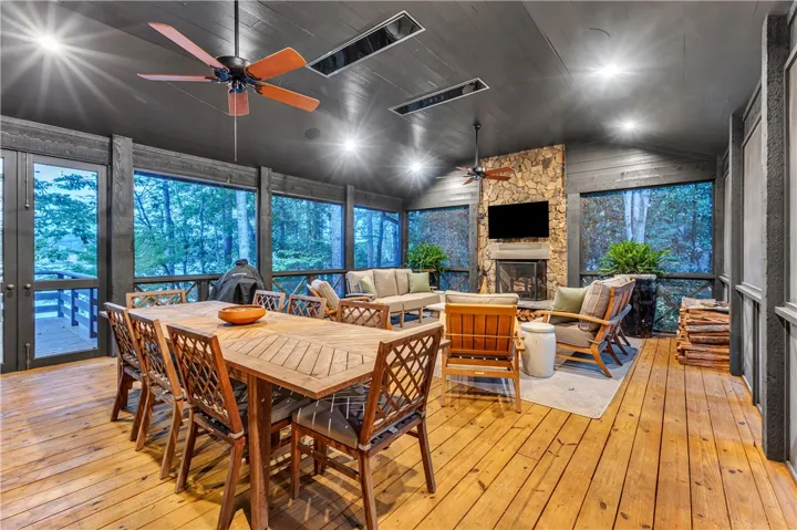 A spacious screened porch with wooden floors, a stone fireplace, and ample room for dining and lounging.