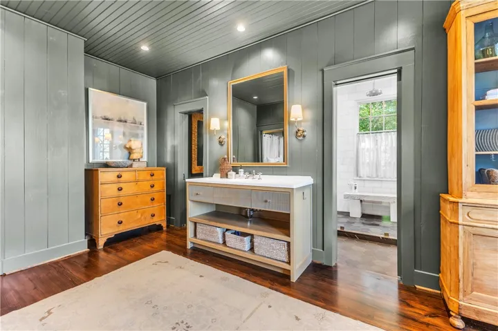Rich hardwood floors lead to a charming vanity area, opening to a private bath retreat.