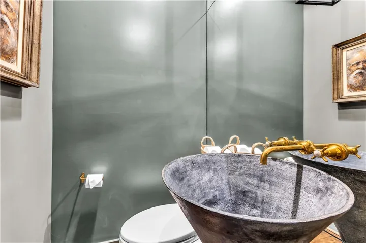 An opulent, antique brass faucet graces a unique, dark metal sink in this sophisticated bath.