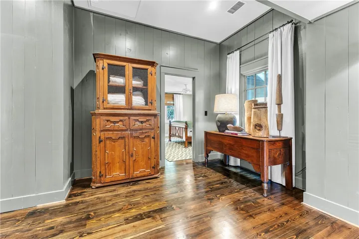 Lustrous hardwood flooring stretches through this inviting entryway, leading to another bright room.