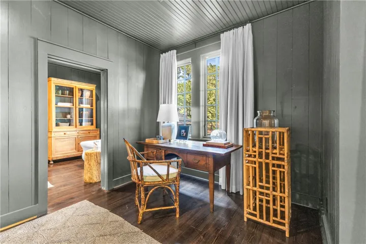 A refined study features rich hardwood flooring and a bright window view.