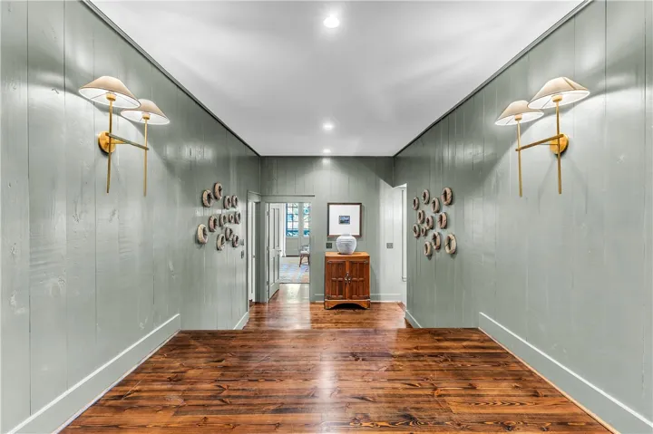 Rich hardwood floors complement paneled walls in this inviting, naturally illuminated hallway.