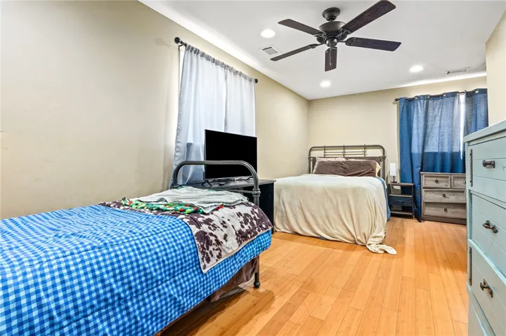 Hardwood floors and recessed lighting elevate this inviting bedroom space.