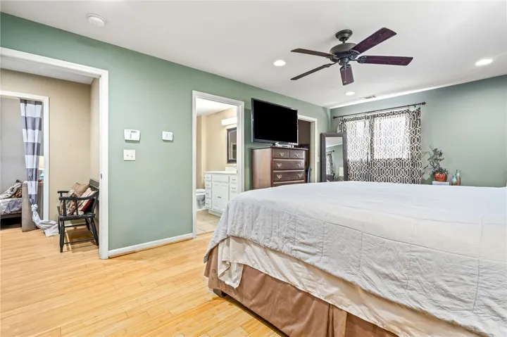 Hardwood floors and a ceiling fan enhance this cozy and functional bedroom space.