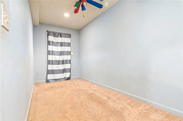 A compact bedroom with soft carpeting provides a cozy, private retreat.