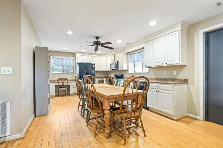 Functional kitchen with ample cabinet space, a ceiling fan, and naturally illuminated dining area.