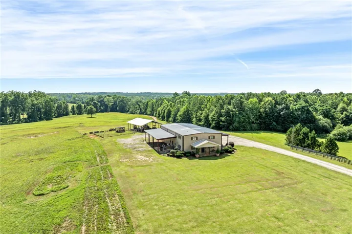 A sweeping aerial view reveals a grand estate nestled within verdant pastures and a dense woodland backdrop.