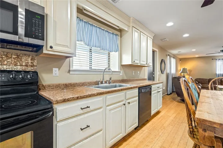 A well-lit kitchen with natural wood flooring offers ample cabinetry and counter space.