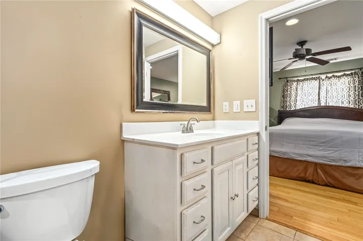 A well-appointed bathroom features a single vanity with ample storage and a clear view into a comfortable adjoining bedroom.