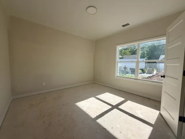 A well-lit bedroom awaits personalization with its broad window and ample space.
